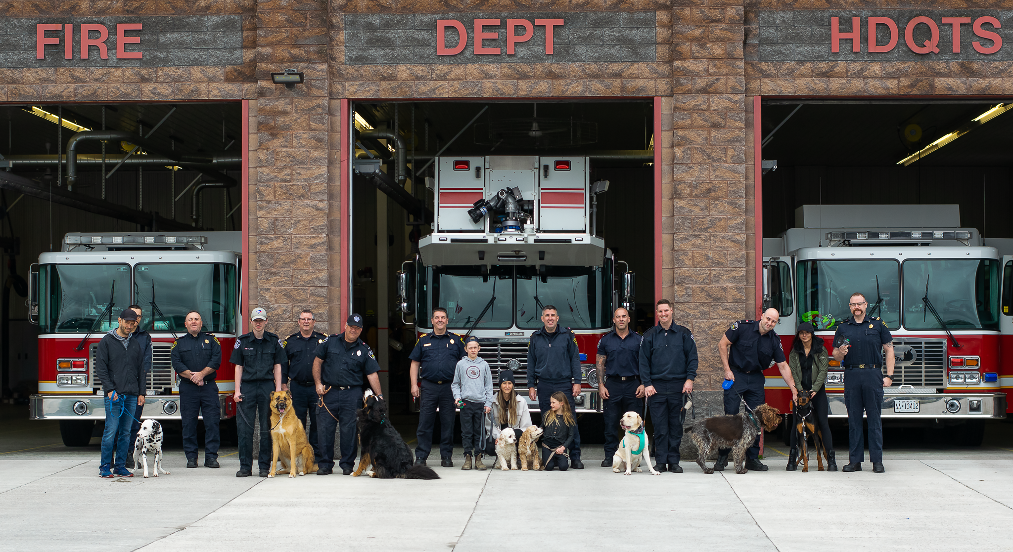Group of people standing infront of fire station with dogs